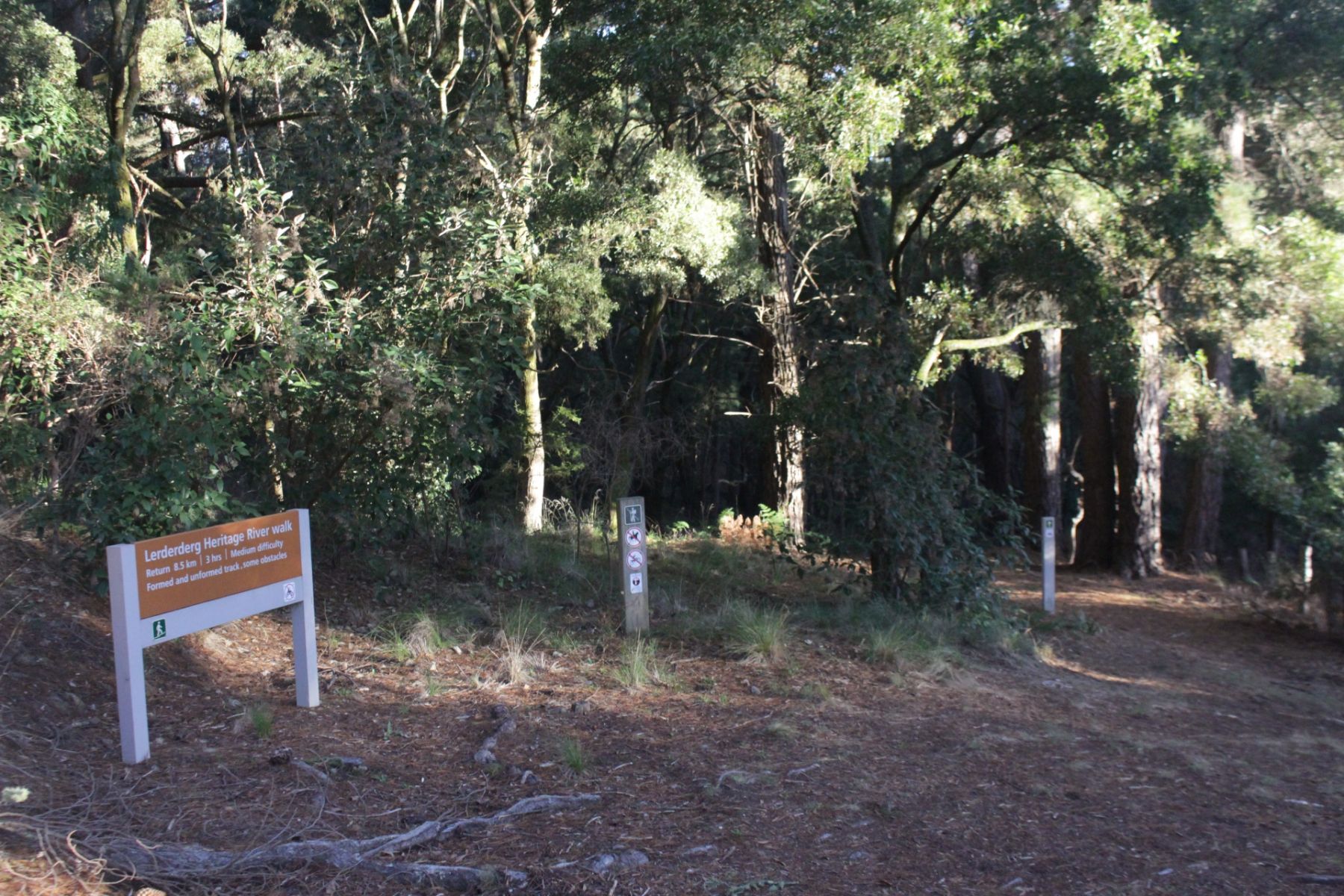 A sign for the Lerderderg Heritage River Walk and the start of the walk among trees