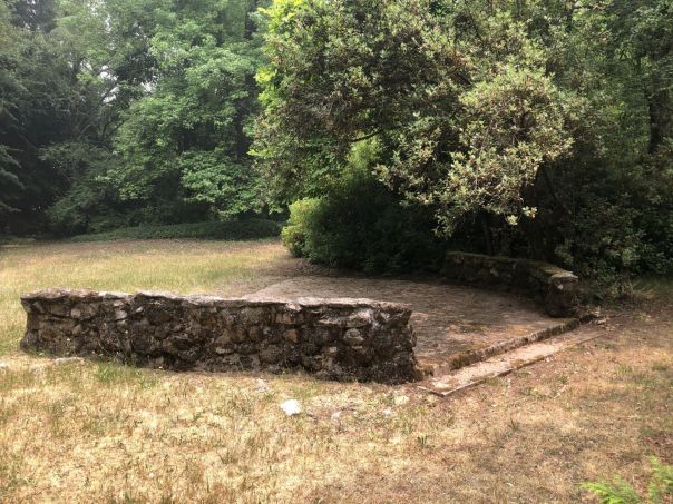 A handcrafted stonewall sits on a patch of grass.