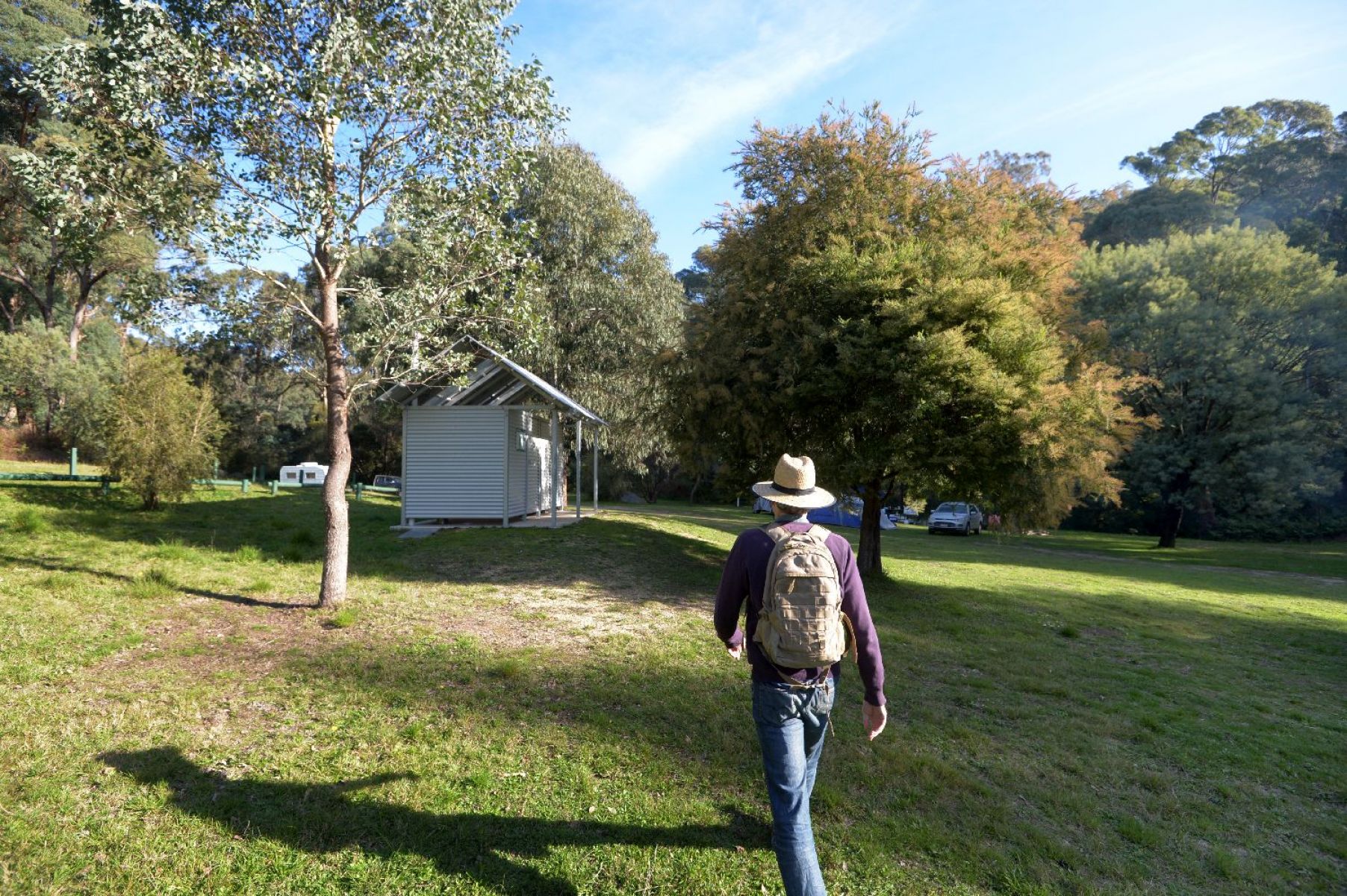 An image of a man walking toward the amenity block situated in the middle of the campground