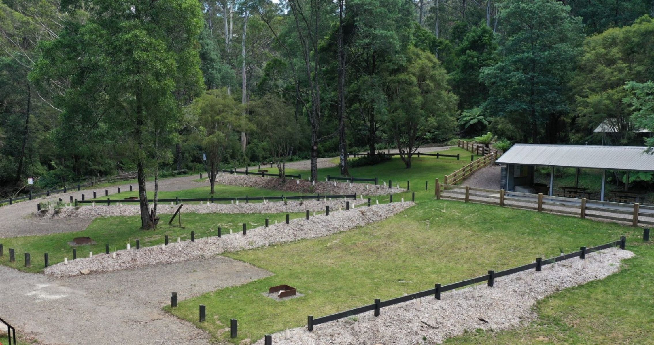 A metal picnic shelter at a spacious campground surrounded by trees