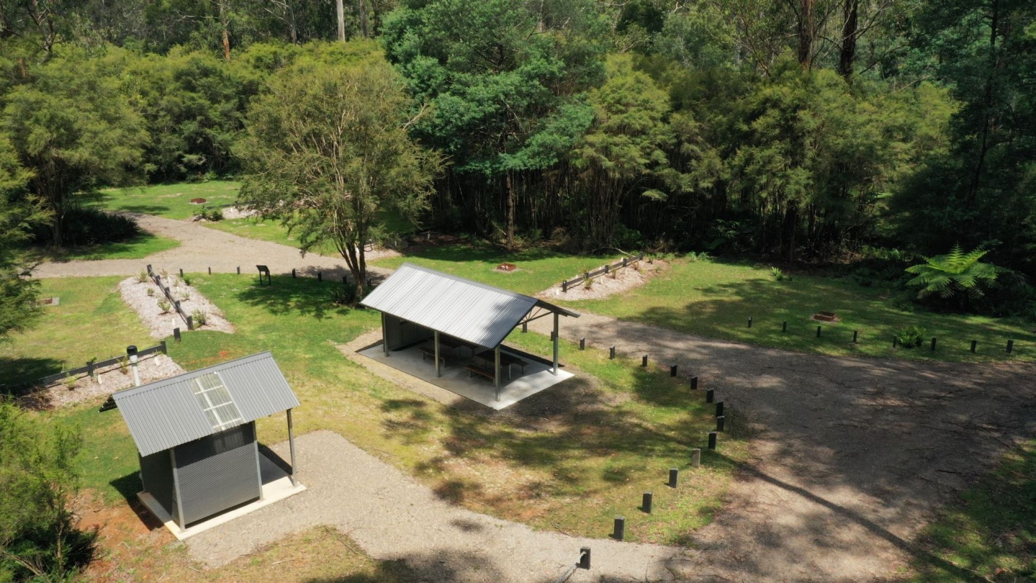 A view over a campground with a gravel road passing through and many flat spots for camping alongside firepits.