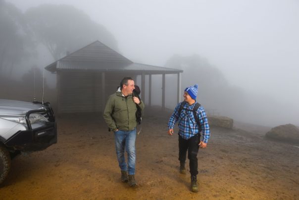 Two men walk from their 4WD against a foggy landscape