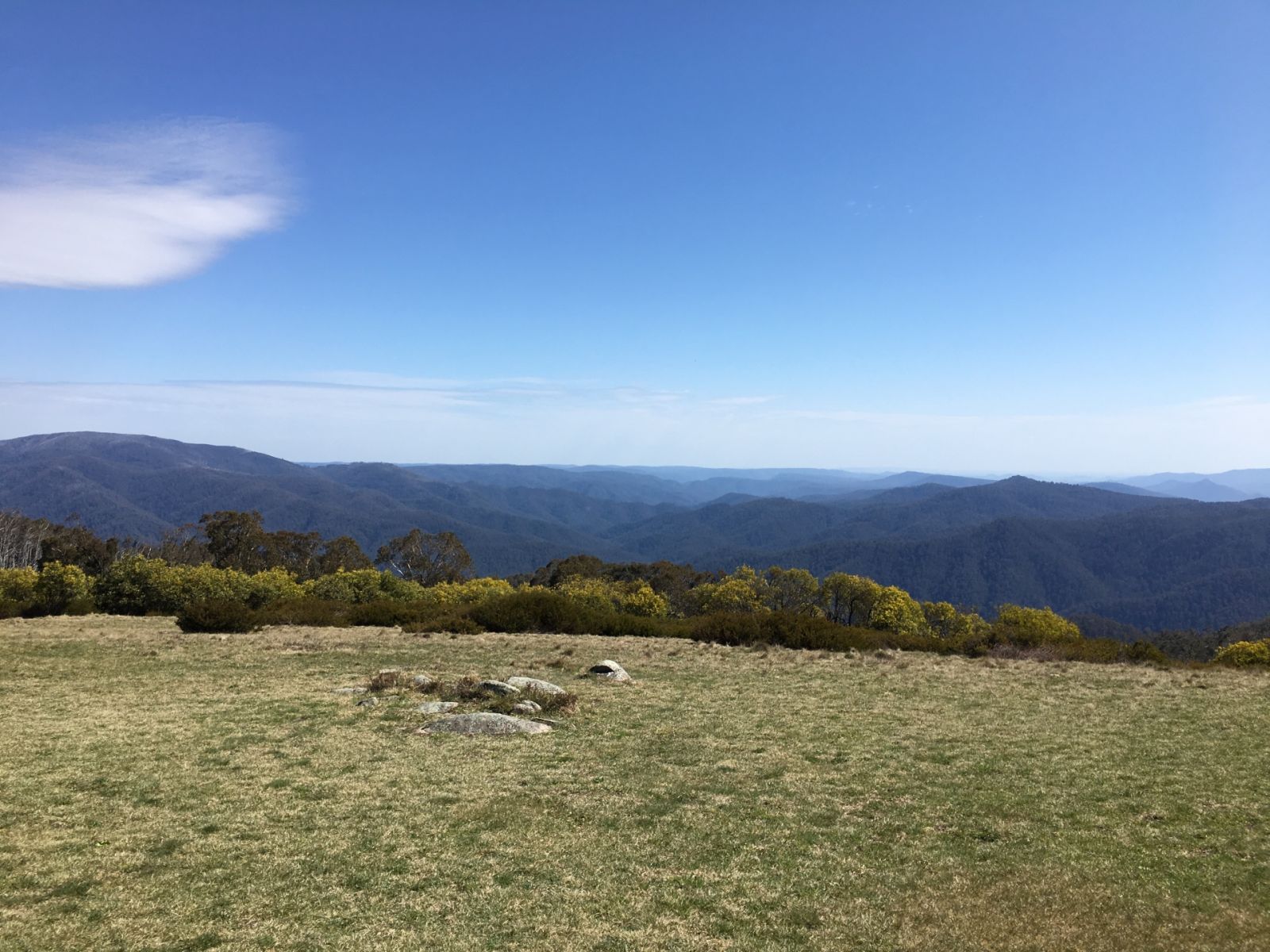 A flat grassy hilltop with wide views of distant mountains