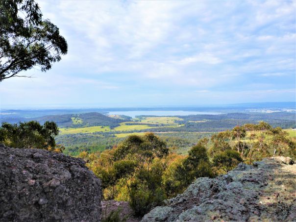 Vast views from a rocky edge across a valley, with a lake and hills in the distance