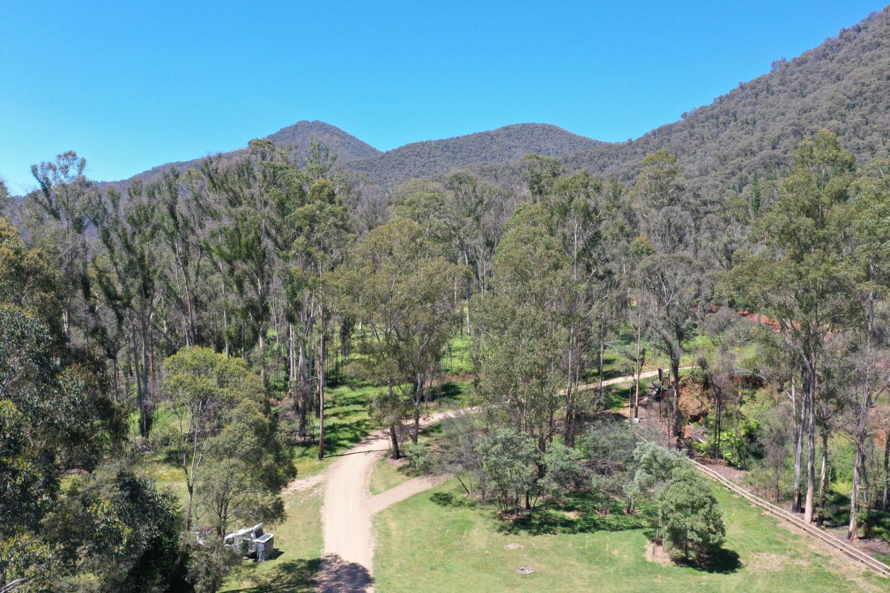 Grassy campground with tree covered mountains in the background. 