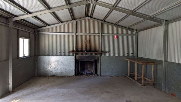 The interior of metal hut with a fire and wooden table inside.