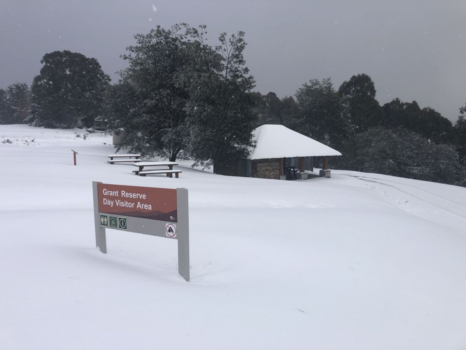 A shelter and surrounding camping area under a blanket of thick snow.