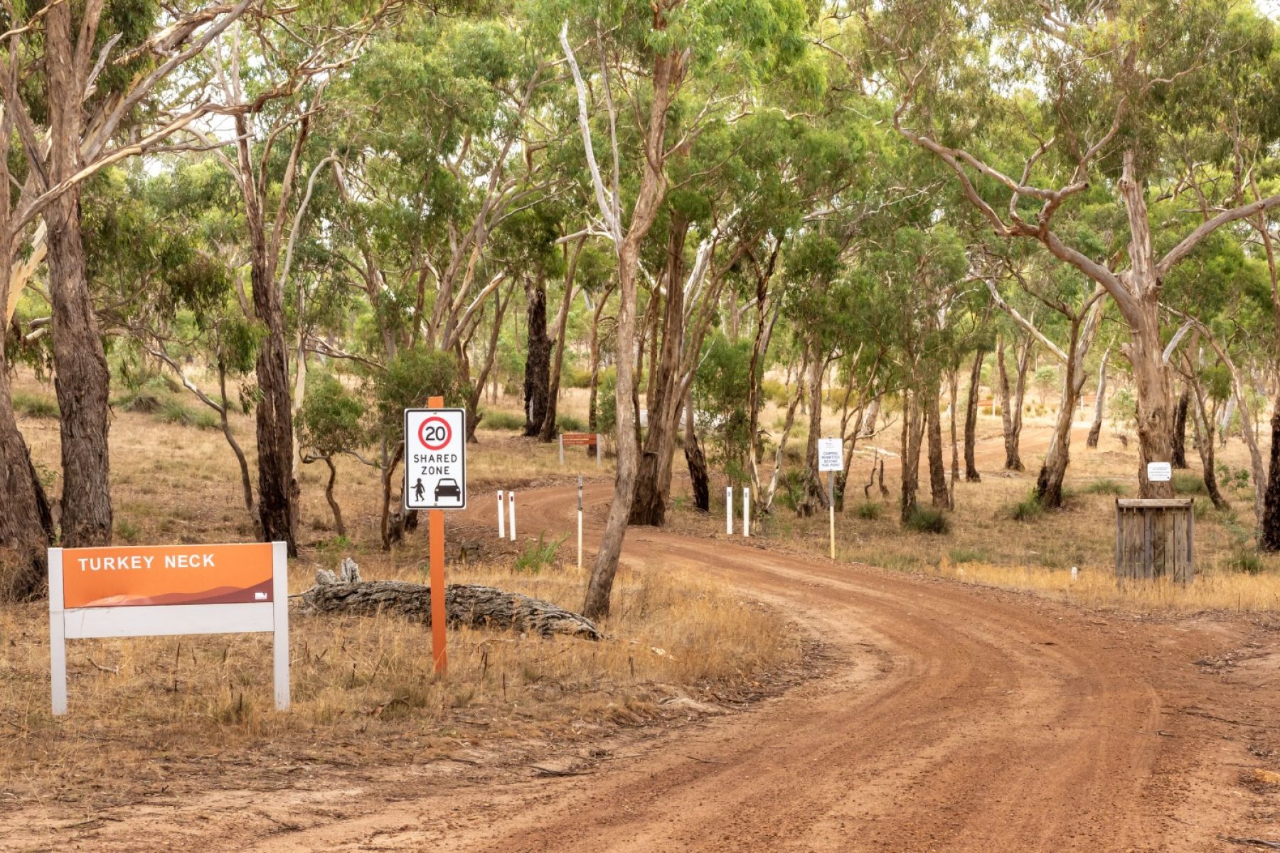 An orange sign next to a dirt road says Turkey Neck 