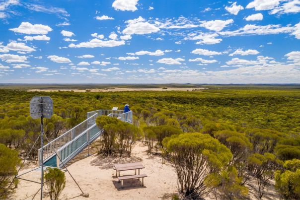 A metal viewing platform providing views over a vast, flat desert