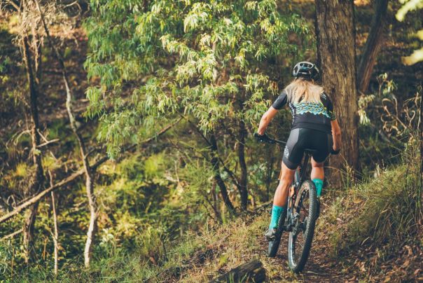 A woman rides a mountain bike through forest