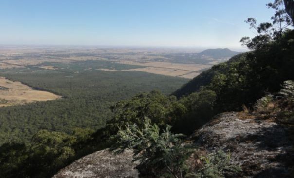 Rocky boulder in foreground looking over surrounding plans and forest 