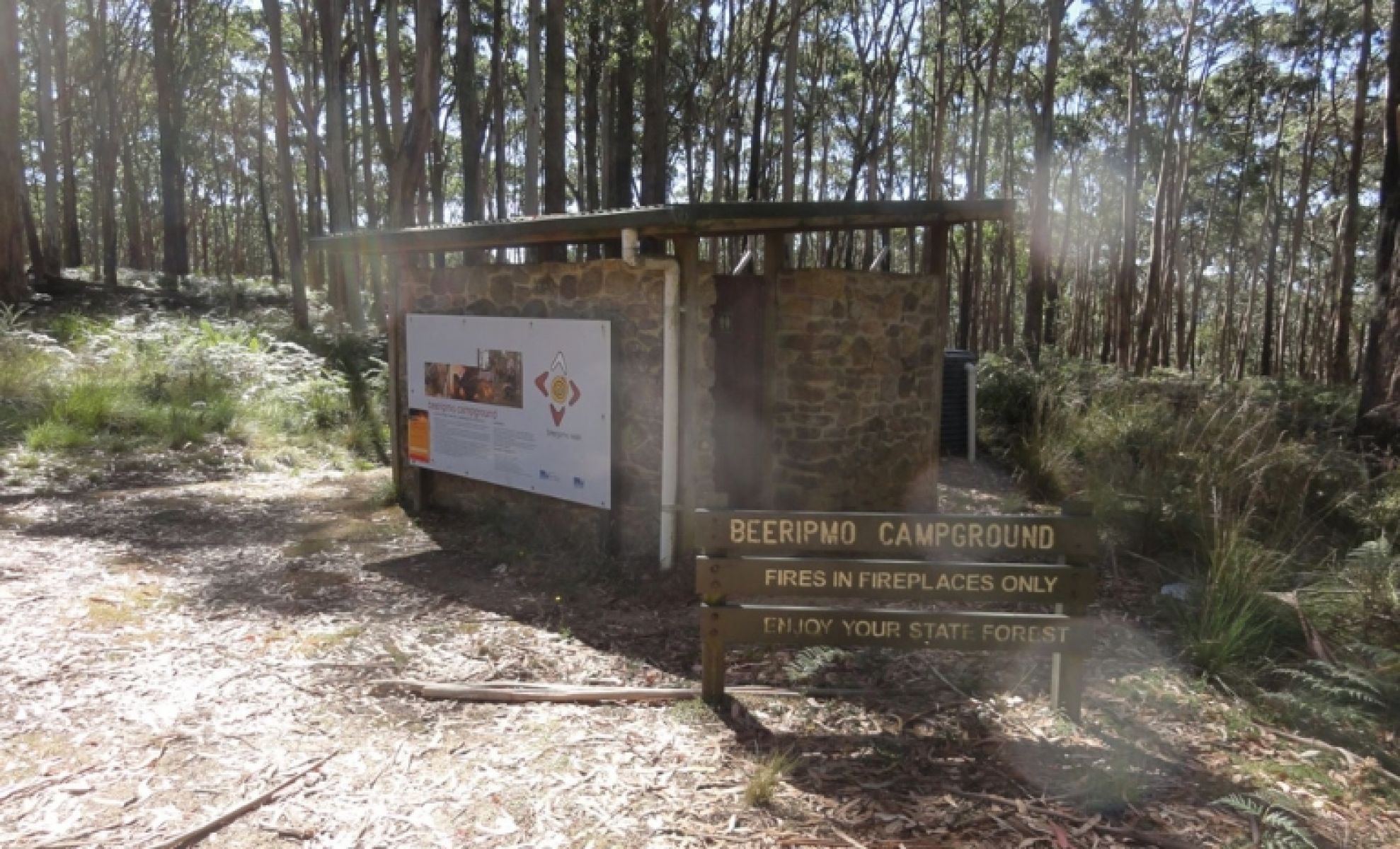 Stone toilet block with signage in the foreground