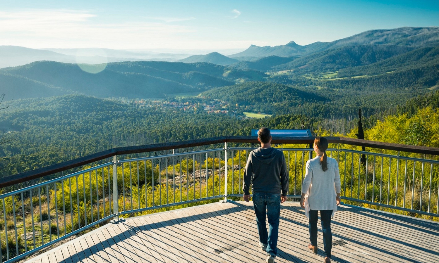 A couple stands on Keppel Lookout enjoying sweeping views over a township sitting in a valley