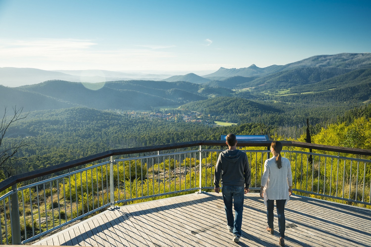 A couple stands on Keppel Lookout enjoying sweeping views over a township sitting in a valley