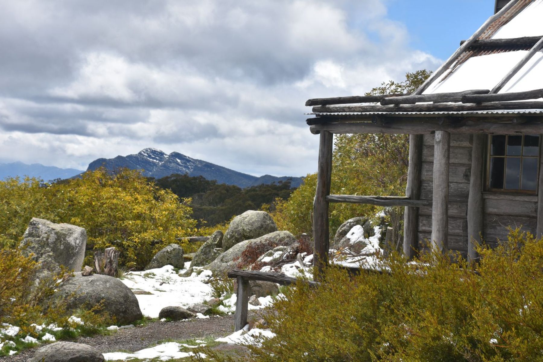 A log hut with fallen snow and mountain views in background