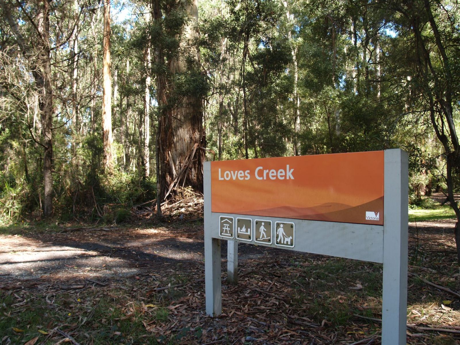 An orange sign says Loves Creek Walk next to a walking track.