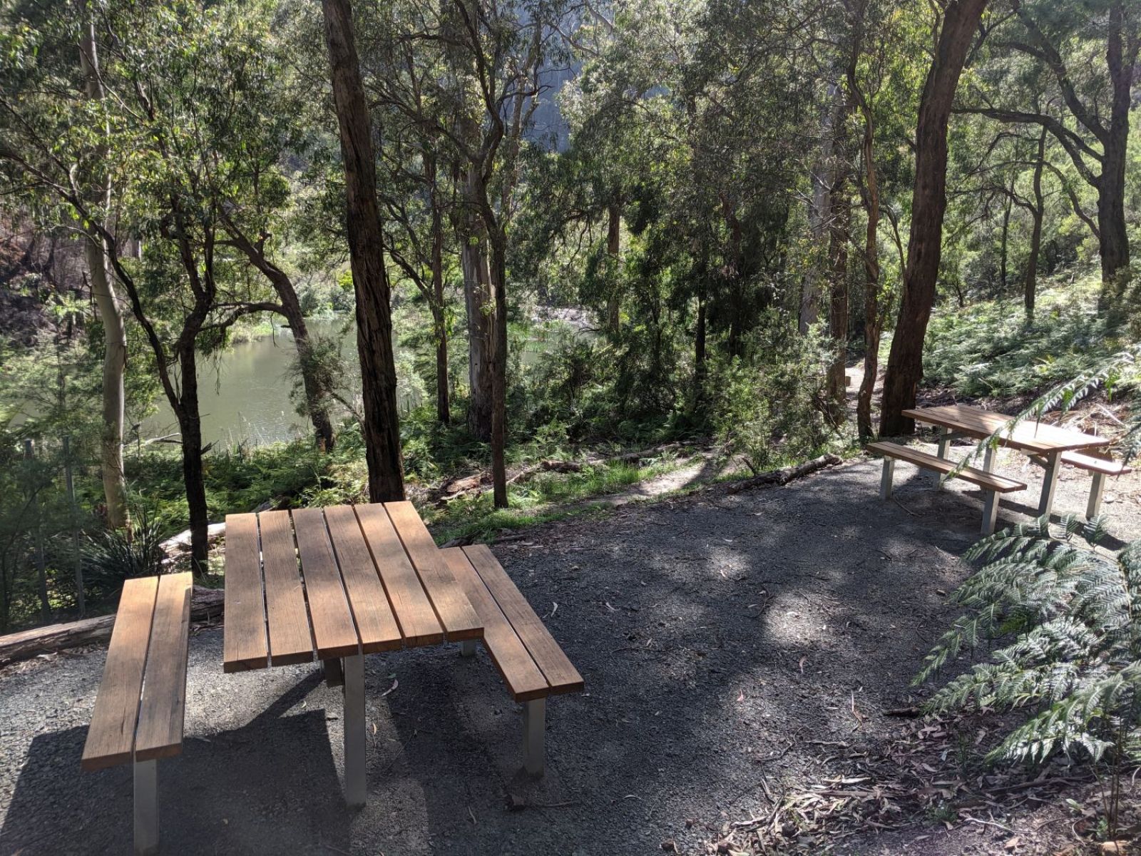 Two picnic tables and chairs along the track looking over the river