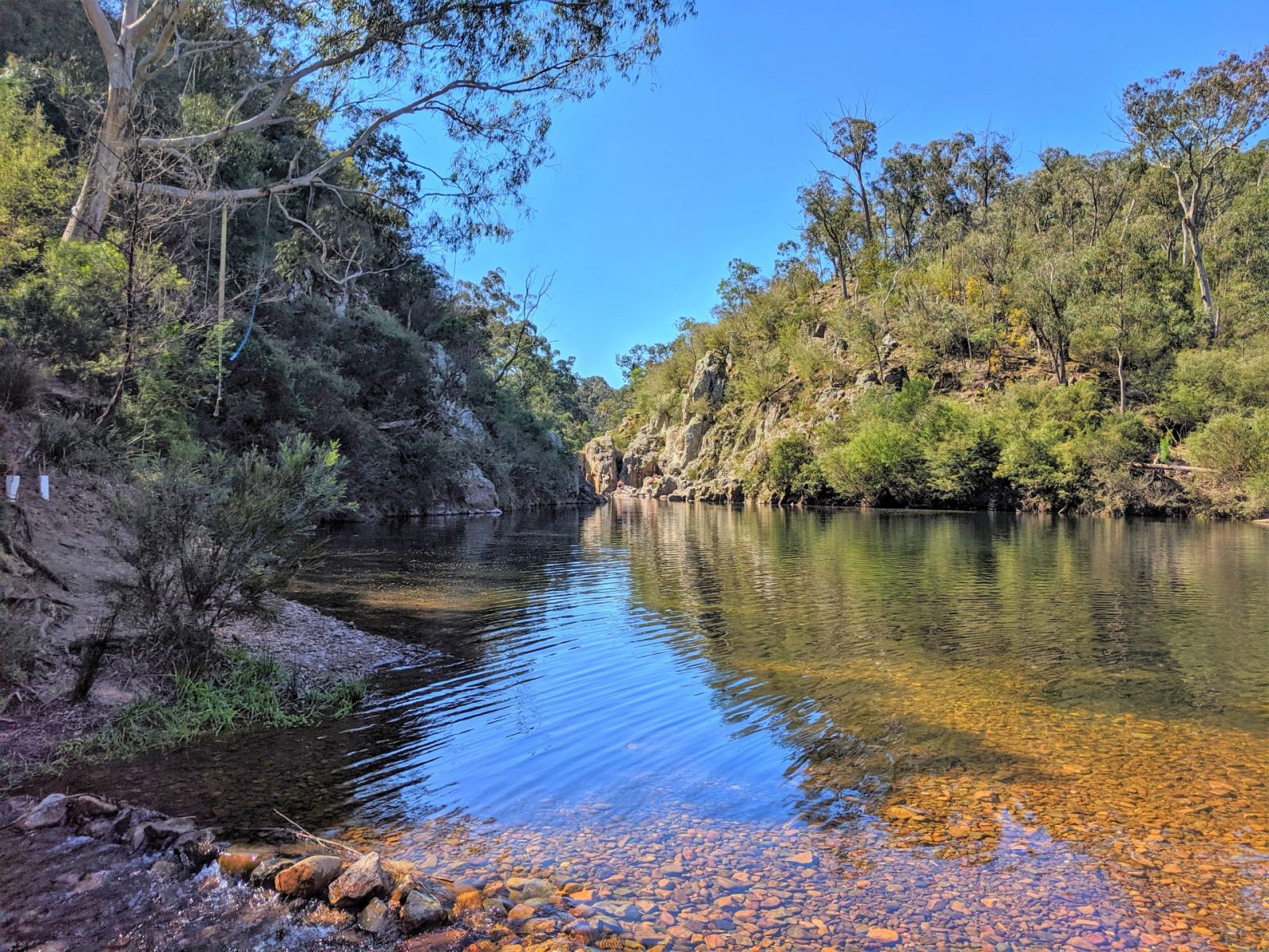 Blue Pool waterhole surrounded by rocks and tree covered hills.   