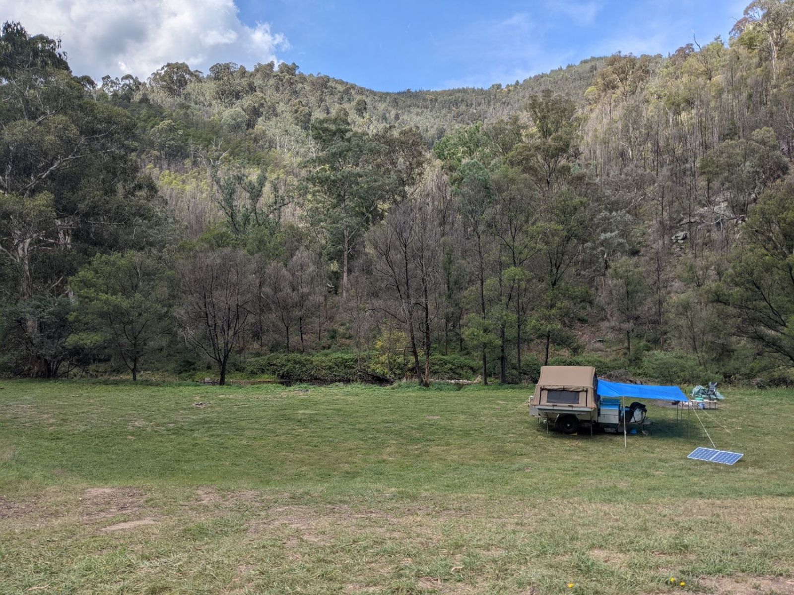 A camper trailer sits in an open grassy field.