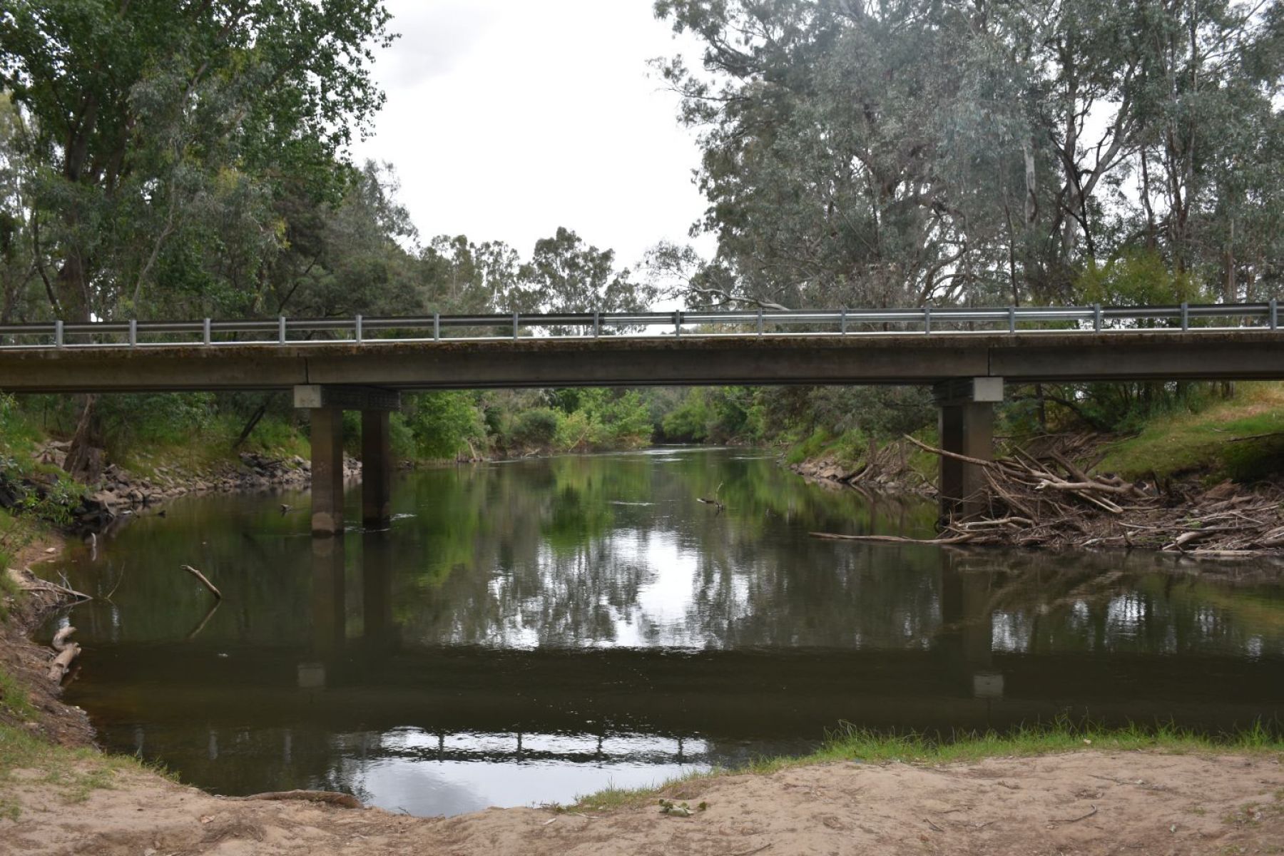 Sandy river bank with a large bridge in background